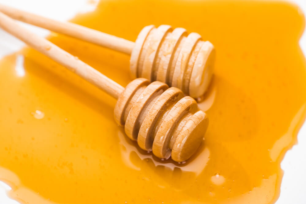 two honey dippers sitting in honey